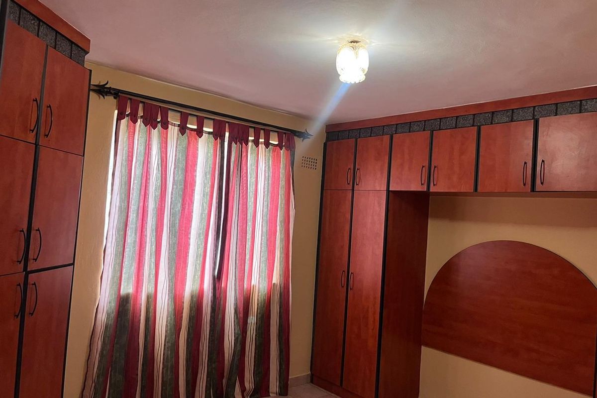 A bedroom featuring extensive built-in wooden cabinetry and tiled flooring, offering ample storage space.