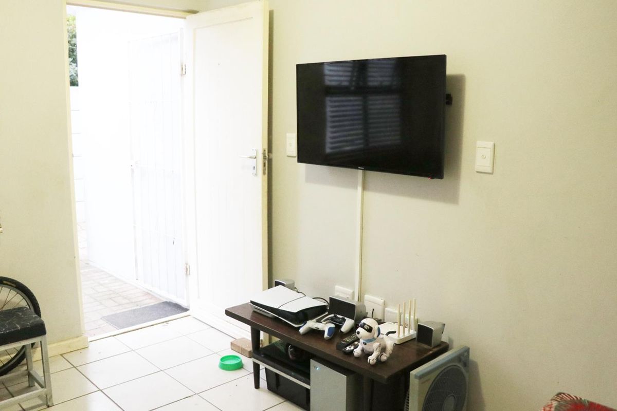 A functional living area featuring tiled flooring and direct access to an outdoor space, with wall-mounted television infrastructure.