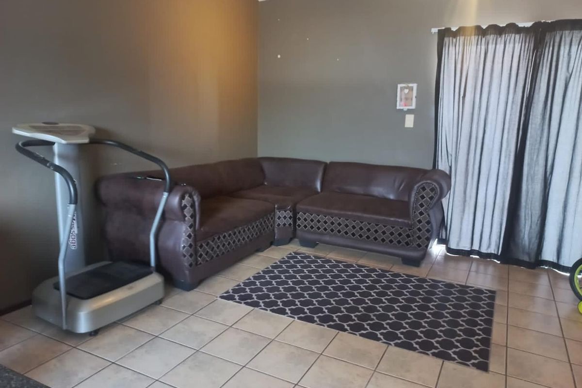 A living room area featuring tiled flooring and a sliding door with curtains, providing access to the exterior.