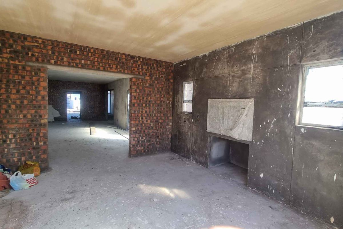 An unfinished interior space featuring exposed brick walls, cement paneling, and raw concrete flooring, offering a blank canvas for complete renovation and customization.