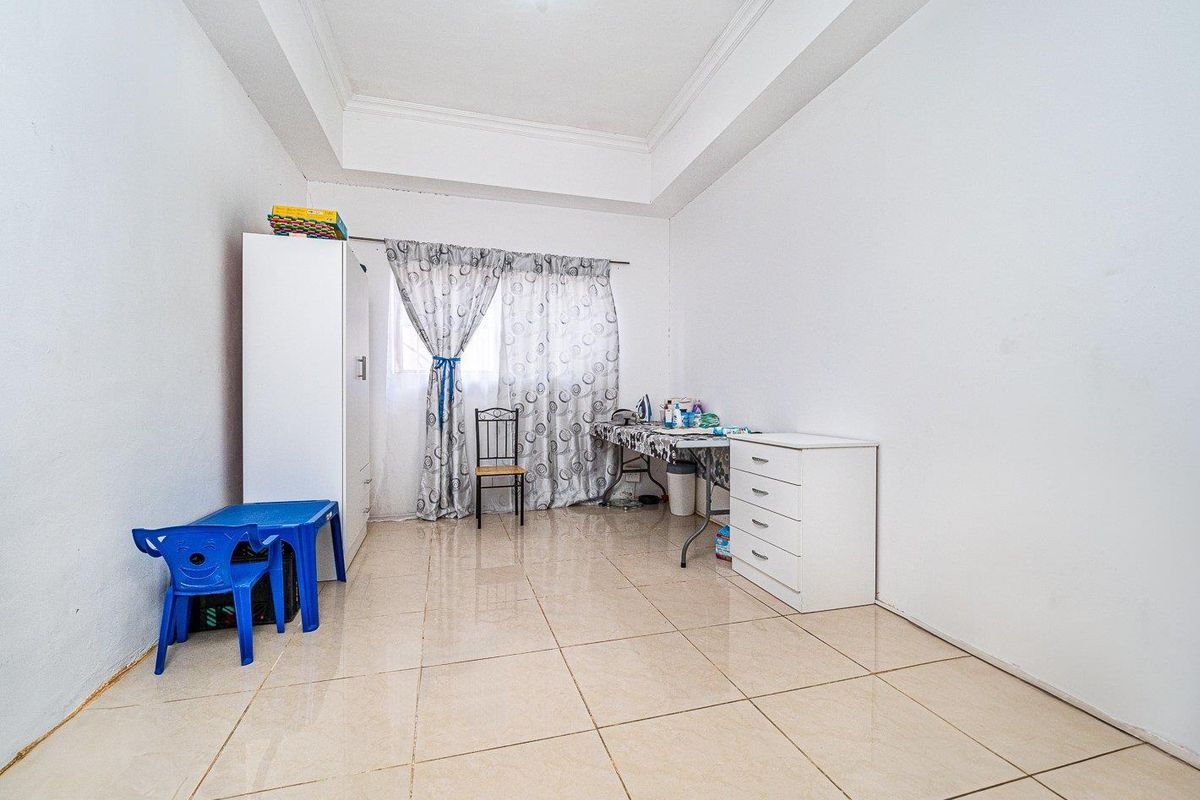 A simple bedroom featuring tiled flooring and a tray ceiling, providing a functional and neutral space.