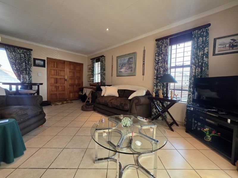 Spacious living room featuring tiled flooring, recessed lighting, and a double wooden entrance door, offering a comfortable and functional layout.
