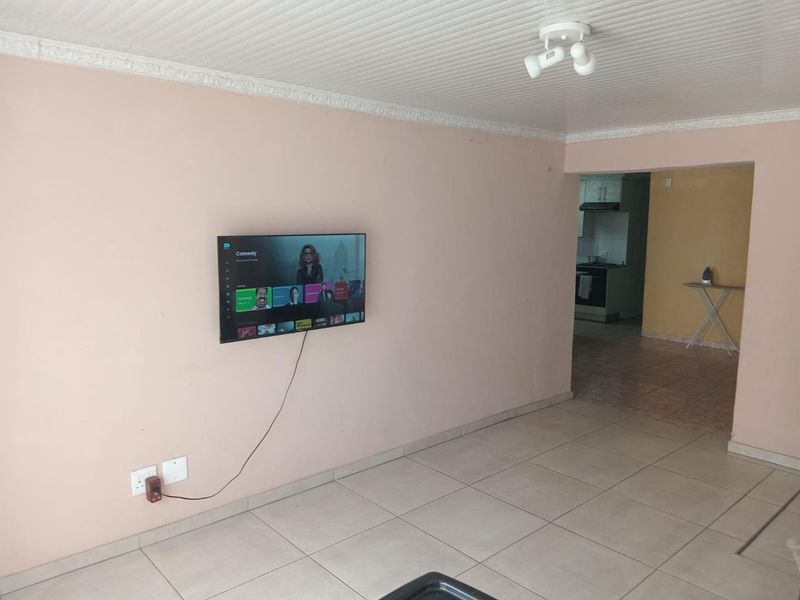 Open plan living area featuring tiled flooring and ceiling cornice, with a direct view into the adjacent kitchen space.