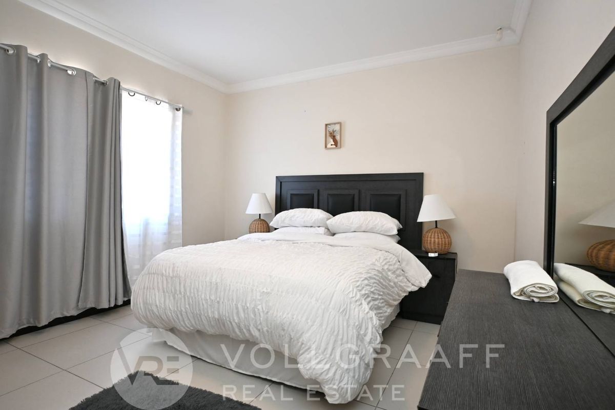 A well-maintained bedroom featuring neutral wall tones, tiled flooring, and decorative ceiling cornicing.