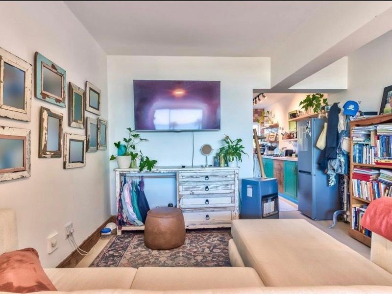 An open-plan living area featuring a wall-mounted television and direct sightlines into the adjacent kitchen space.
