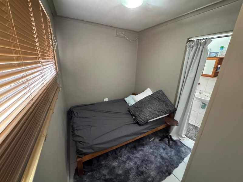 Compact bedroom featuring tiled flooring, venetian blinds, and direct access to an en-suite bathroom.