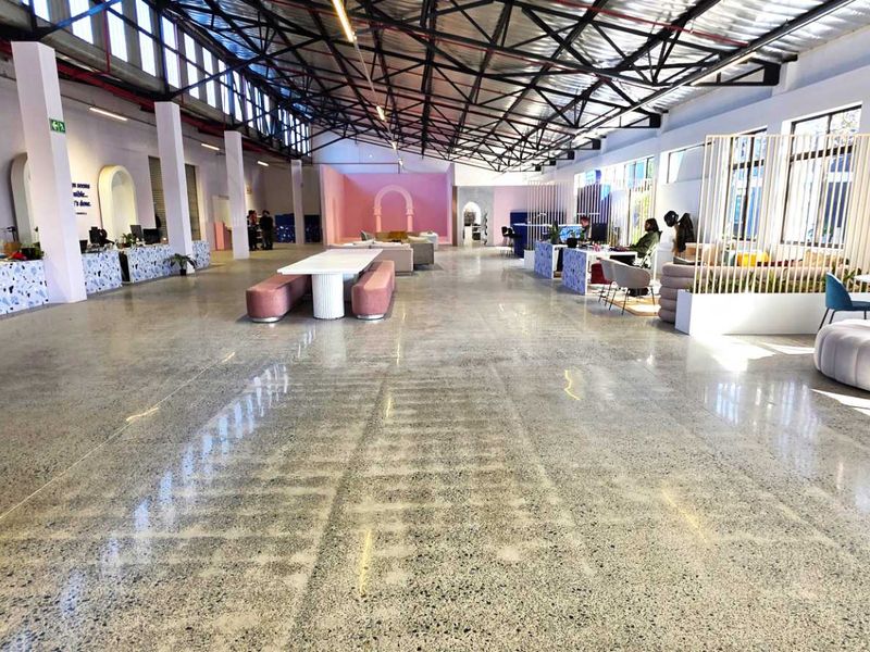 Spacious open-plan industrial office area featuring polished concrete floors, high exposed steel roof trusses, and abundant natural light from clerestory windows.