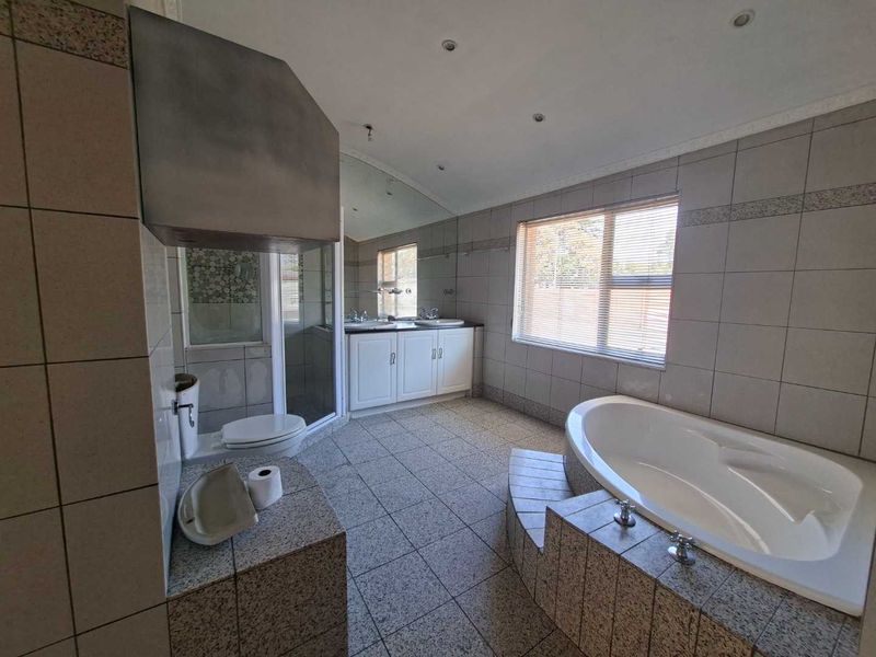 Spacious bathroom featuring a corner bathtub, tiled shower enclosure, and a dual-basin vanity with ample storage.