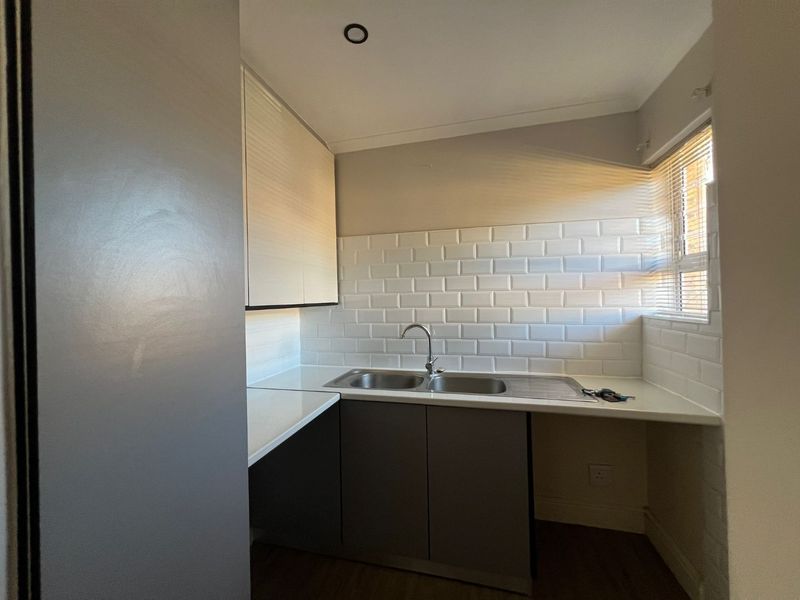 A clean and functional scullery area featuring modern subway tile backsplash, double bowl sink, and fitted cabinetry with ample counter space.