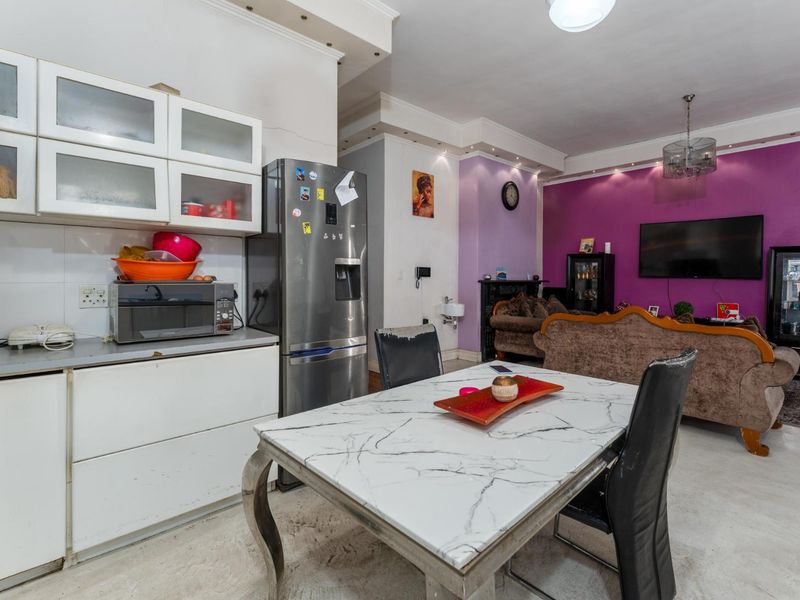 Open-plan living and kitchen area featuring built-in cabinetry, recessed ceiling lighting, and a distinct purple accent wall in the lounge space.