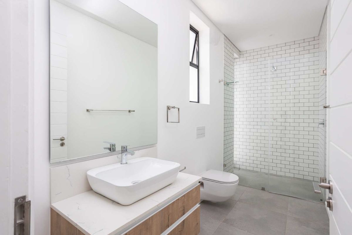 Modern bathroom featuring a vessel sink on a stone-topped vanity, wall-mounted toilet, and a spacious walk-in shower with subway tile finishes.