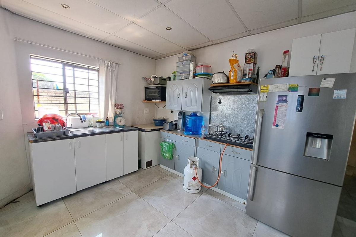 Functional kitchen featuring tiled flooring, built-in cabinetry, stainless steel sink, and gas hob setup with integrated extractor fan.