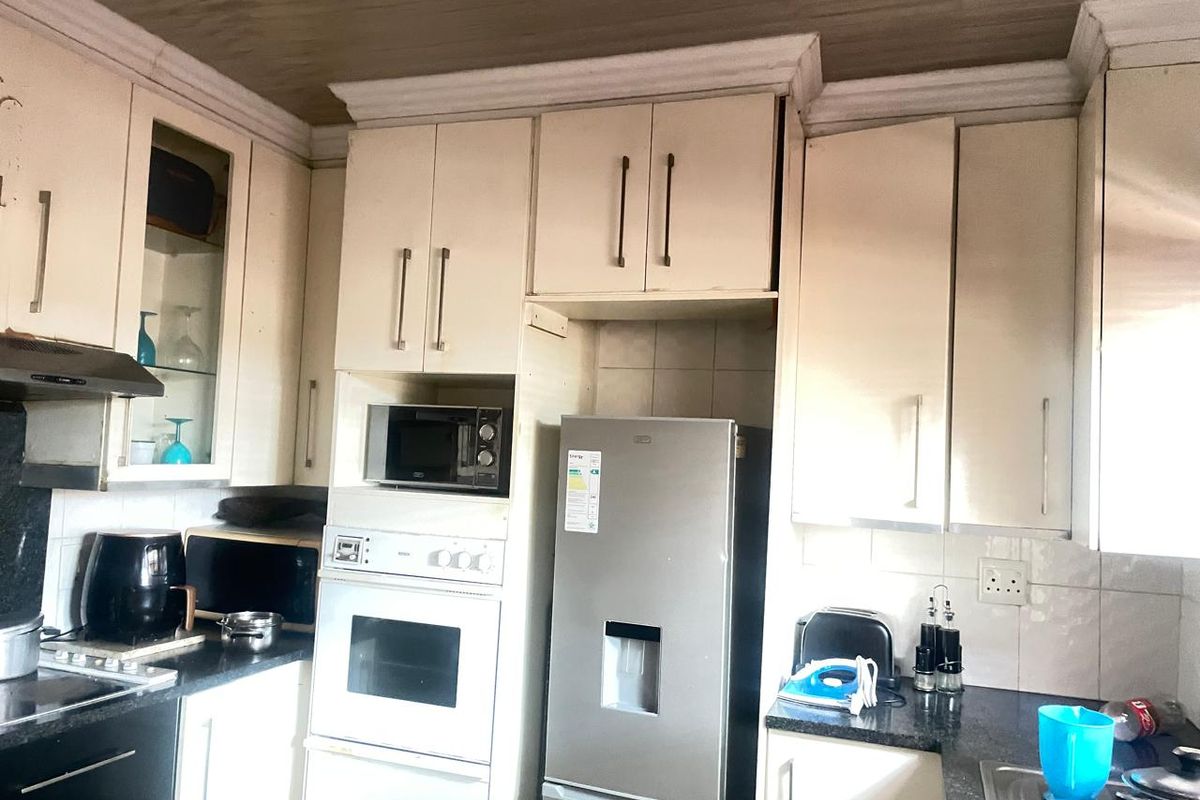 A functional kitchen featuring built-in cabinetry, integrated oven, extractor fan, and granite countertops, offering a practical layout for daily meal preparation.