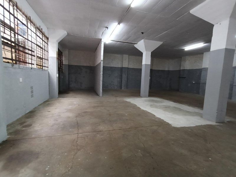 Spacious industrial utility area featuring concrete flooring, exposed structural columns, and fluorescent lighting, suitable for storage or workshop use.