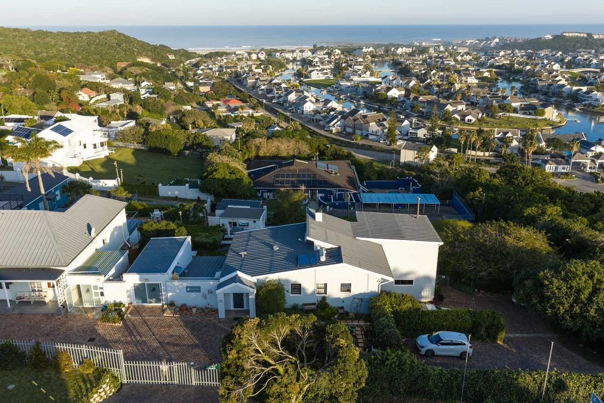 Aerial view of the property showcasing the roof structure, solar panels, paved driveway, and surrounding residential estate landscape.