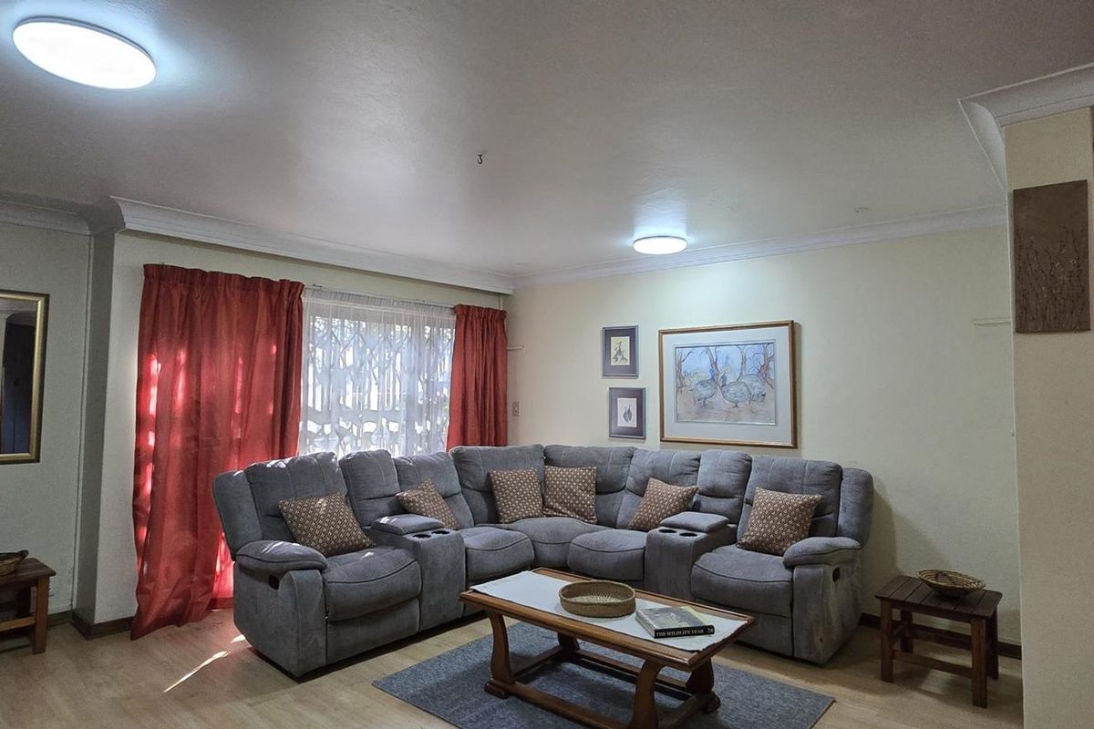 A comfortable living room featuring laminate flooring, coving, and neutral wall tones, providing a functional and inviting space for relaxation.