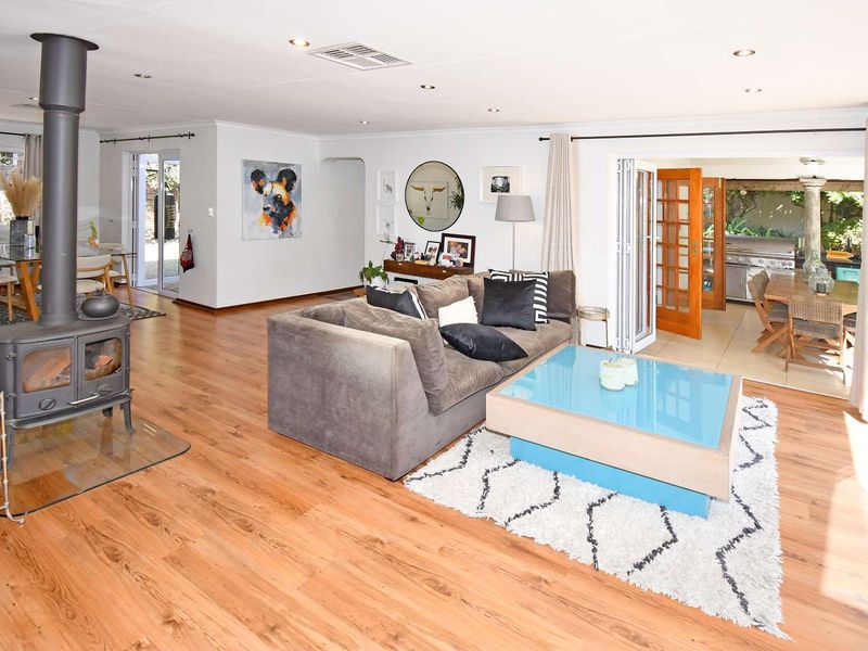 Spacious open-plan living area featuring warm laminate flooring, a prominent freestanding wood-burning fireplace, and seamless access to the outdoor patio through bi-fold doors.
