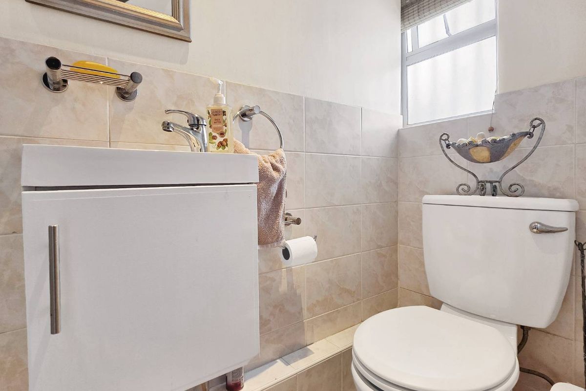 A compact, well-maintained bathroom featuring a wall-mounted vanity, ceramic tiling, and a standard toilet suite.
