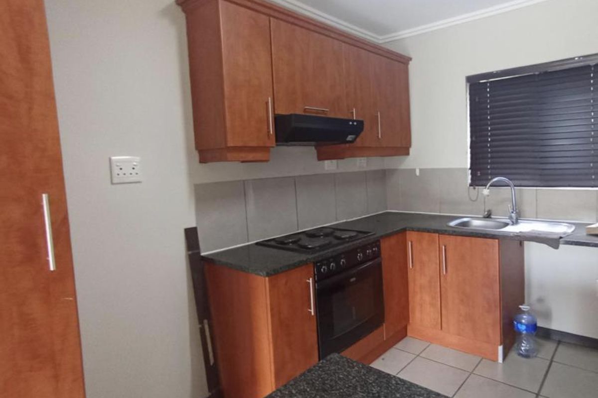 A functional kitchen featuring wood-finish cabinetry, granite countertops, a built-in oven with hob, and a tiled backsplash.