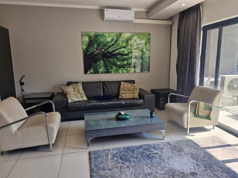 A living room featuring tiled flooring, a wall-mounted split-system air conditioner, and a large sliding glass door providing access to the exterior.