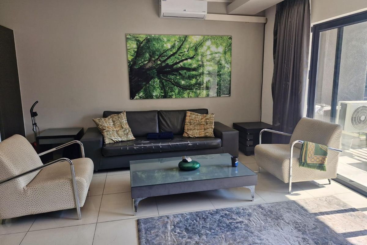 A living room featuring tiled flooring, a wall-mounted split-system air conditioner, and a large sliding glass door providing access to the exterior.