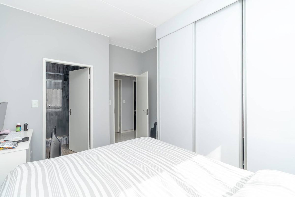 A bright bedroom featuring built-in sliding door wardrobes and direct access to an en-suite bathroom.