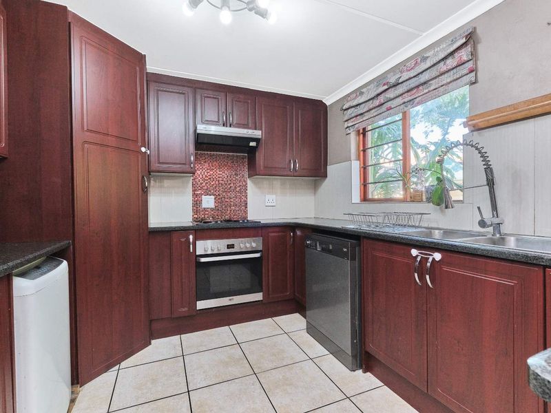 Functional kitchen featuring dark wood cabinetry, granite countertops, built-in oven, gas hob, and a mosaic tile backsplash.