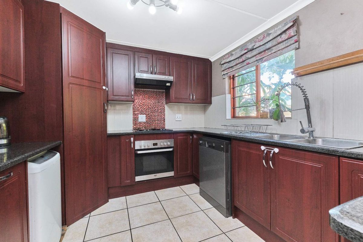 Functional kitchen featuring dark wood cabinetry, granite countertops, built-in oven, gas hob, and a mosaic tile backsplash.