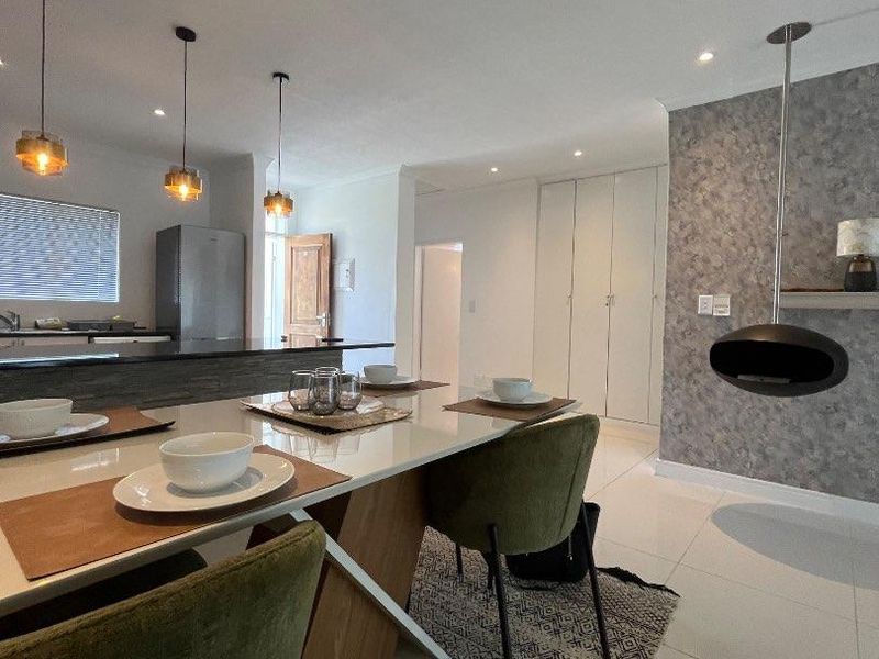 Modern open-plan living and dining area featuring a unique suspended fireplace, sleek tiled flooring, and a functional kitchen island with pendant lighting.