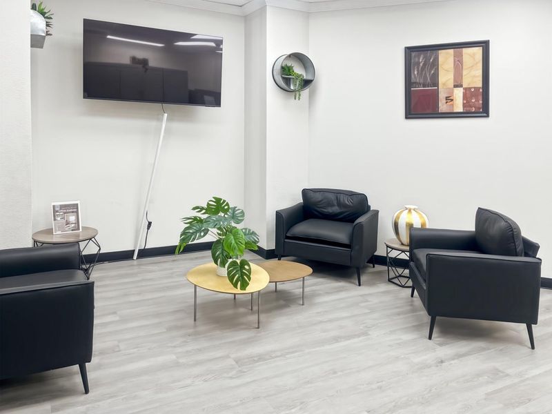 A modern office waiting area featuring light wood-look laminate flooring and clean white walls, providing a professional and welcoming atmosphere.