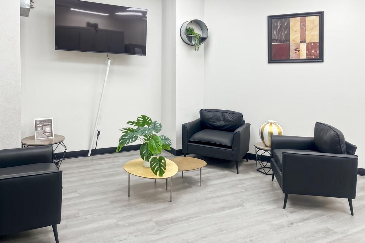 A modern office waiting area featuring light wood-look laminate flooring and clean white walls, providing a professional and welcoming atmosphere.