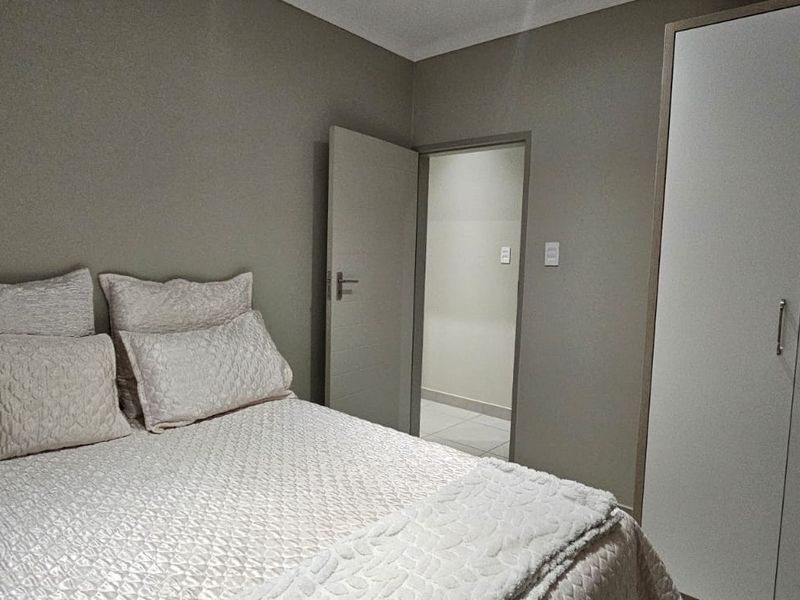 A well-maintained bedroom featuring neutral wall tones and a functional built-in wardrobe with clean finishes.