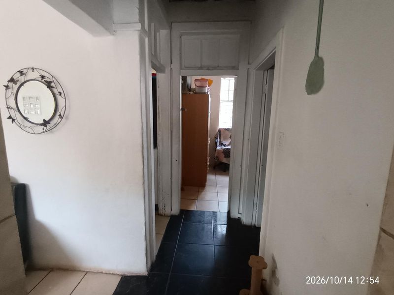 A narrow interior hallway featuring tiled flooring and traditional door frames, connecting multiple rooms within the property.