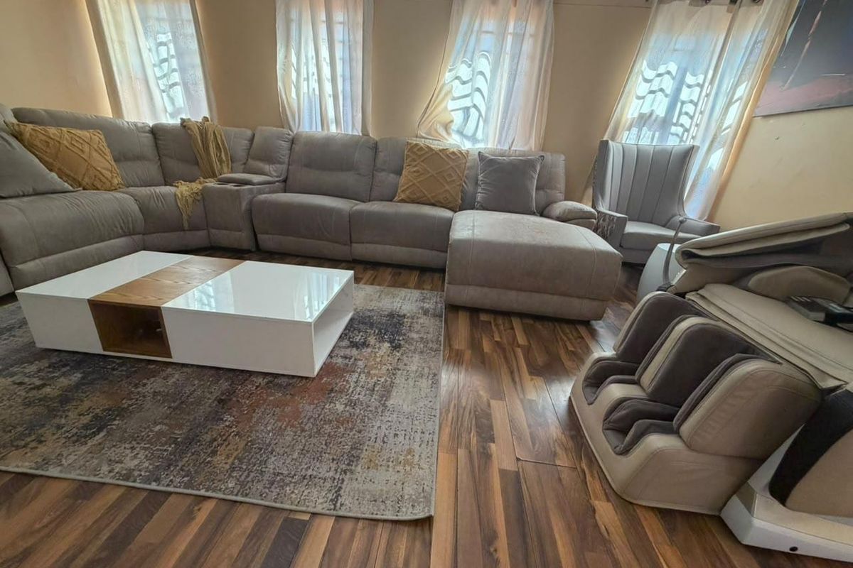 A living room featuring dark wood-look laminate flooring and multiple windows with installed curtain rods.