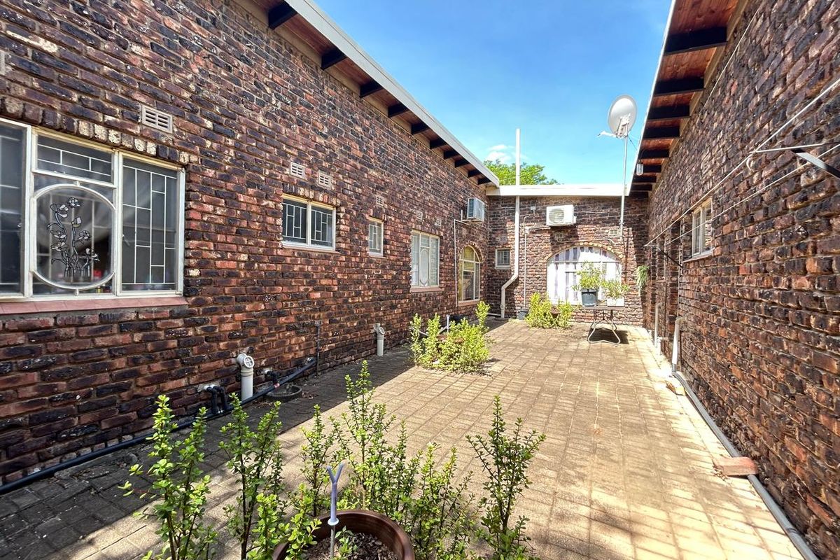 A private rear courtyard featuring exposed brick walls, paved flooring, and integrated air conditioning units.
