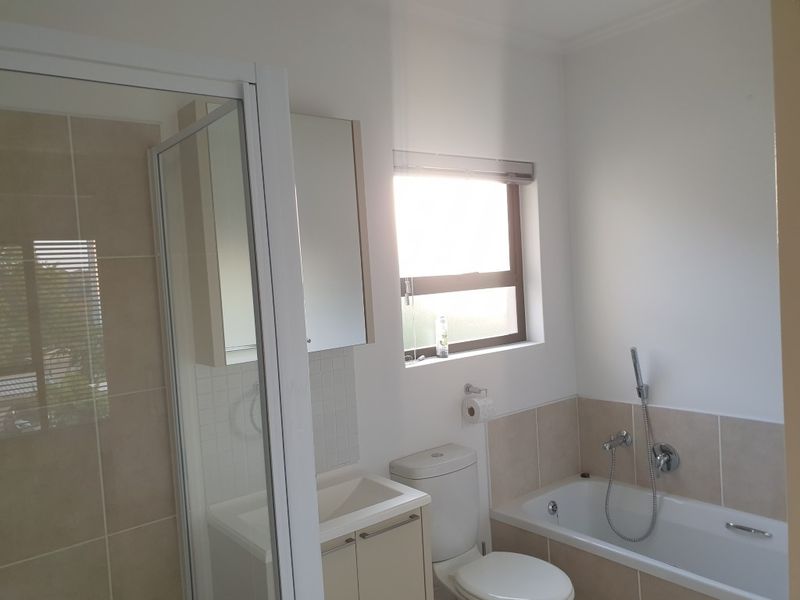 A clean, functional bathroom featuring a separate glass-enclosed shower, a bathtub with handheld shower attachment, and a built-in vanity cabinet.