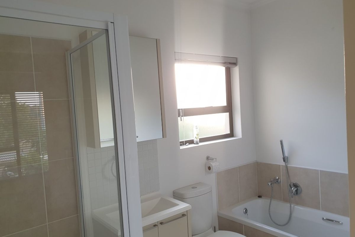 A clean, functional bathroom featuring a separate glass-enclosed shower, a bathtub with handheld shower attachment, and a built-in vanity cabinet.