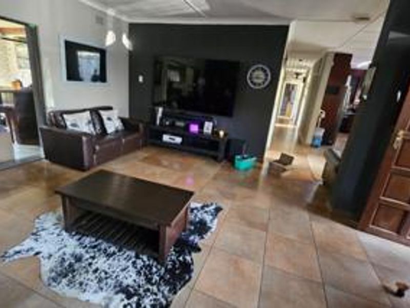 A spacious living room featuring tiled flooring and a dark accent wall, providing a comfortable area for relaxation and entertainment.