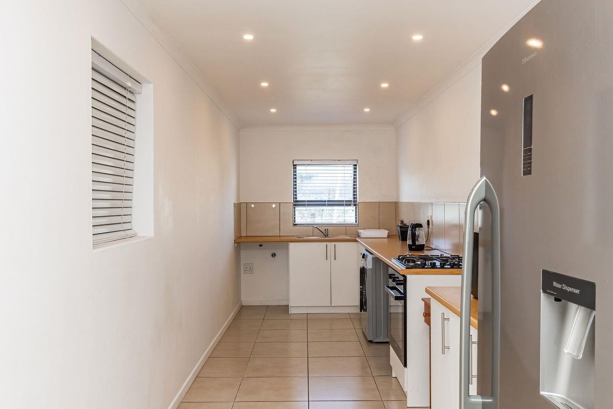 A functional galley-style kitchen featuring tiled flooring, built-in cabinetry, a gas hob, and an integrated oven with tiled splashbacks.
