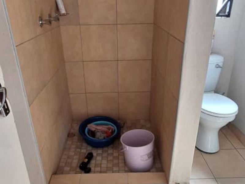 A functional bathroom featuring a walk-in shower area with tiled walls and a standard toilet, offering potential for modernization and cosmetic updates.