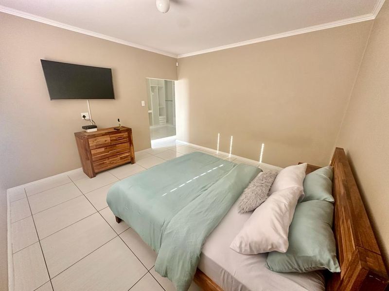 A well-maintained bedroom featuring neutral wall tones, tiled flooring, and direct access to an adjoining walk-in closet area.