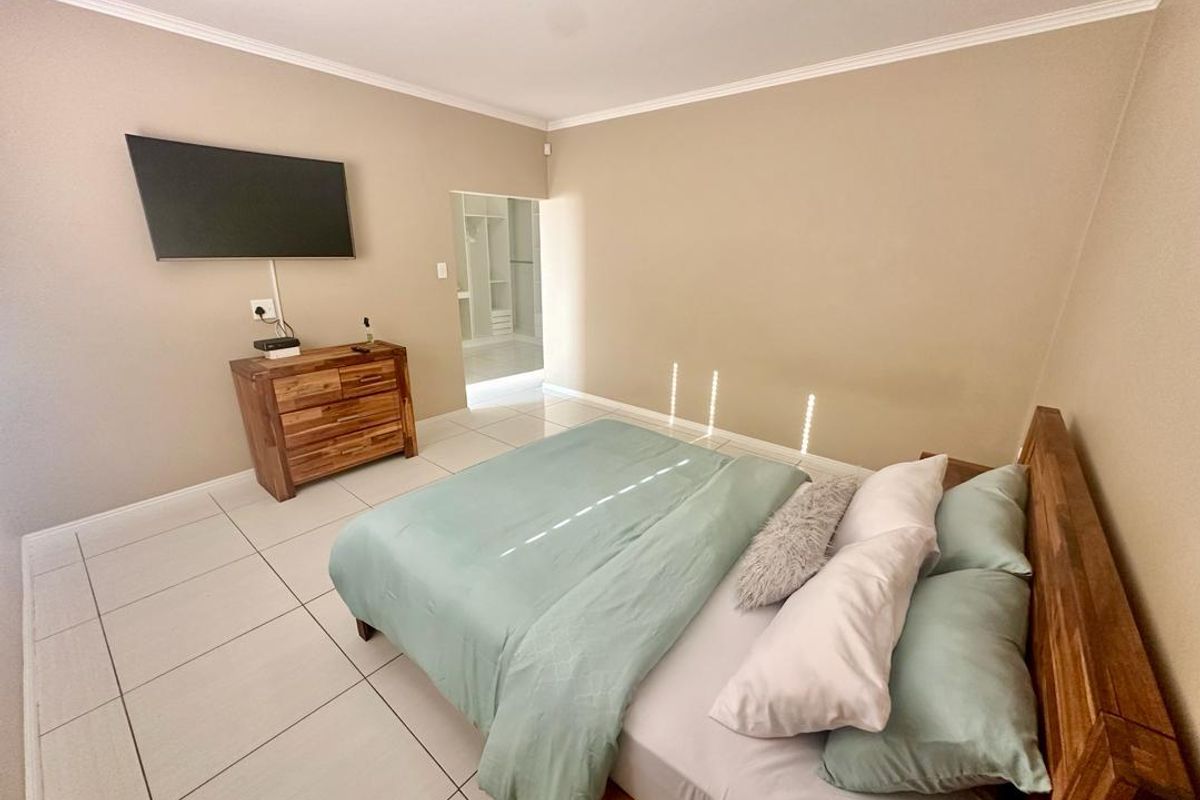 A well-maintained bedroom featuring neutral wall tones, tiled flooring, and direct access to an adjoining walk-in closet area.