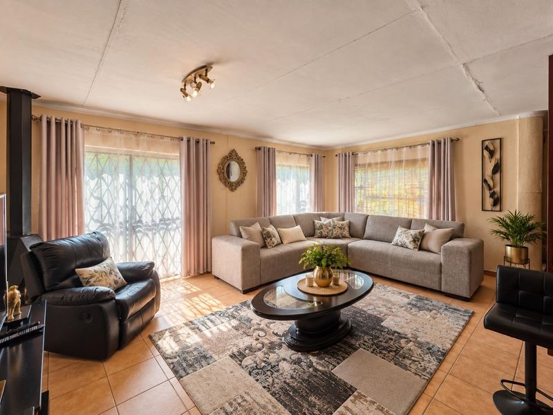 Spacious living room featuring tiled flooring, a wood-burning fireplace, and large sliding doors with security gates, providing ample natural light.