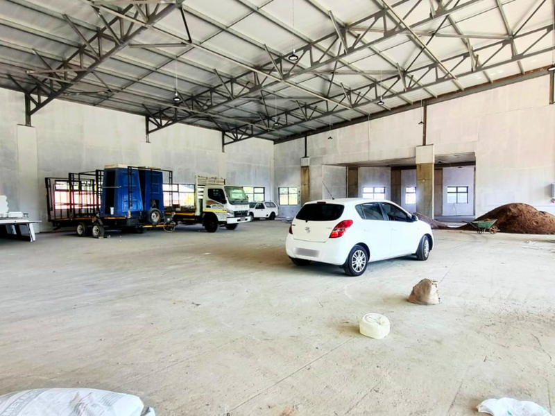A large, open-plan industrial utility space featuring exposed steel roof trusses, concrete flooring, and high ceilings, suitable for storage or workshop use.