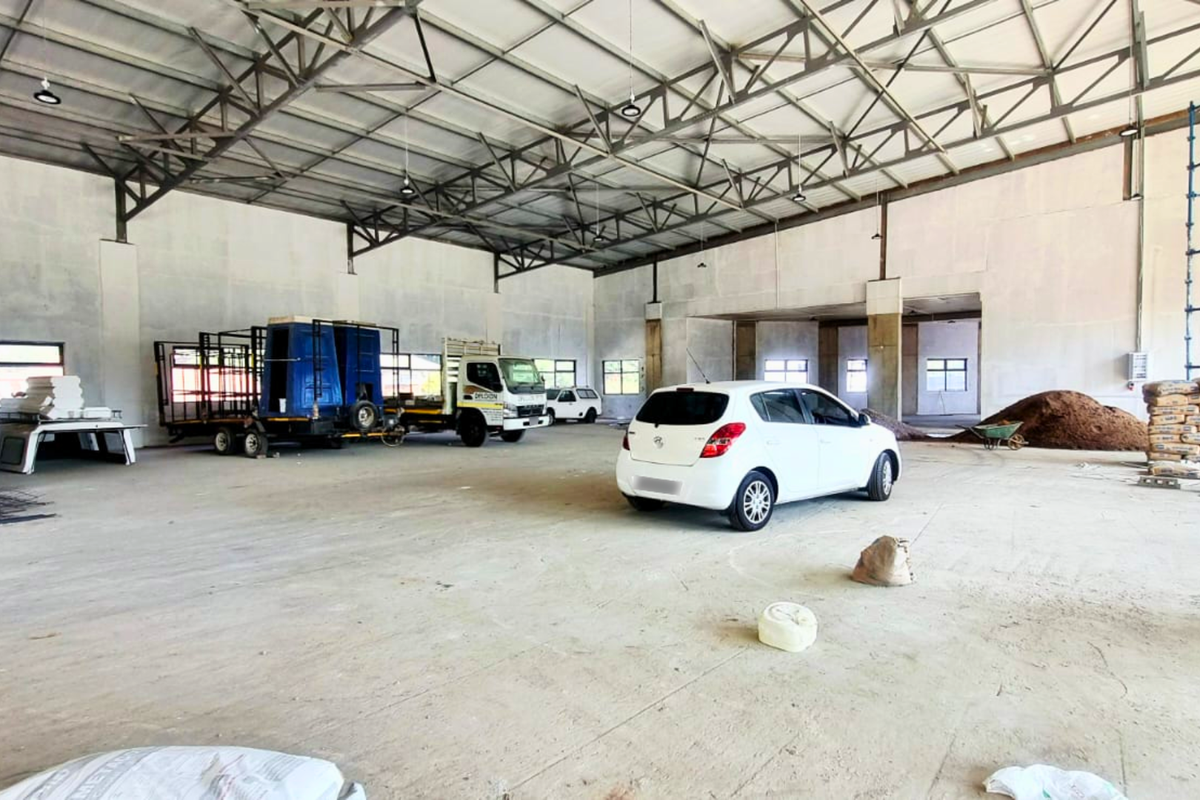 A large, open-plan industrial utility space featuring exposed steel roof trusses, concrete flooring, and high ceilings, suitable for storage or workshop use.