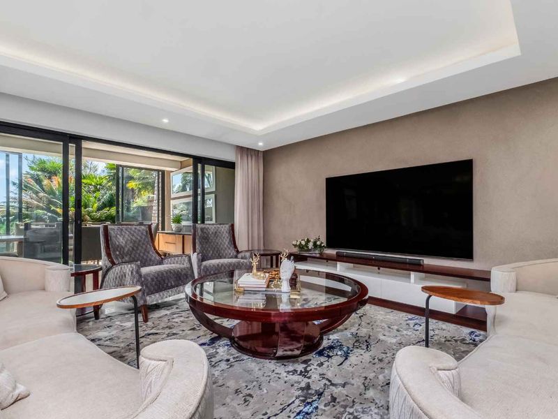 A well-appointed living room featuring recessed cove lighting and large sliding glass doors that provide seamless access to the outdoor patio area.