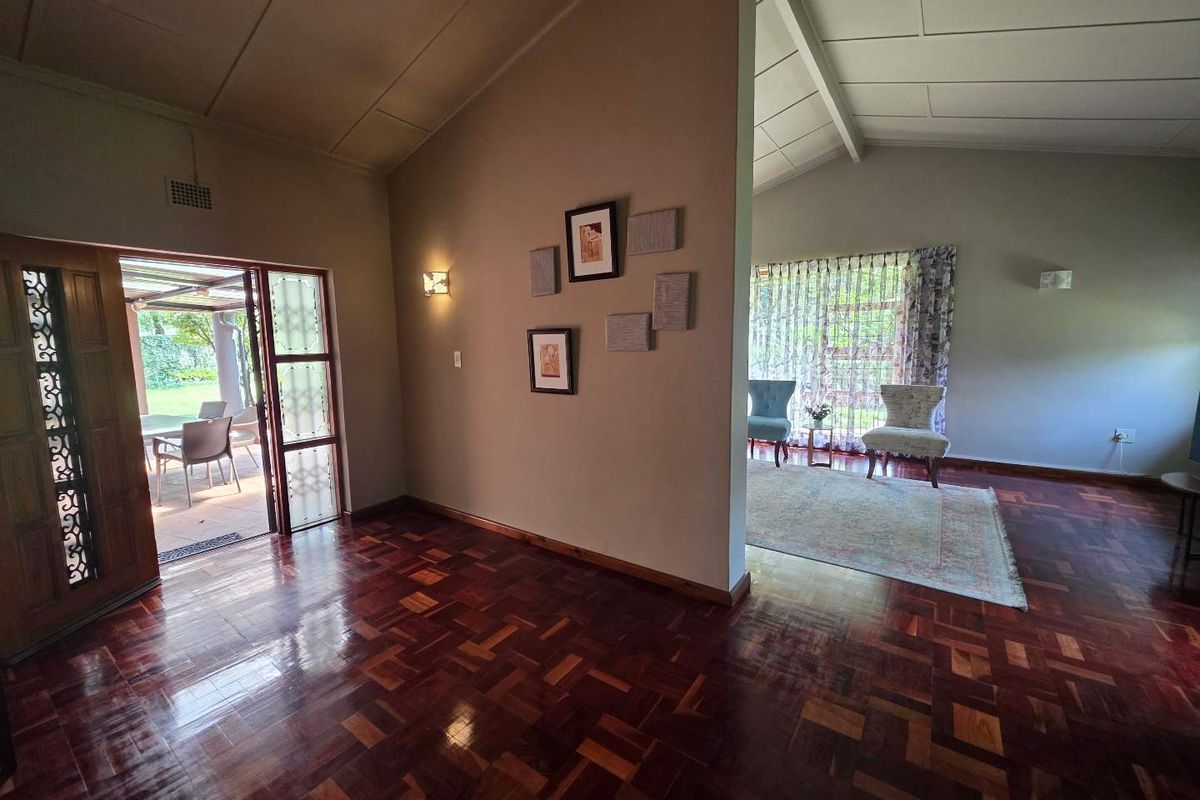 Spacious living area featuring polished parquet timber flooring, vaulted ceilings, and direct access to an outdoor patio through a decorative timber door.