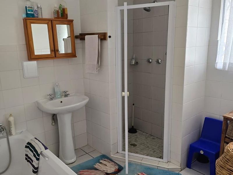 A functional bathroom featuring a pedestal basin, a separate shower enclosure, and a built-in bathtub with white ceramic wall and floor tiling.