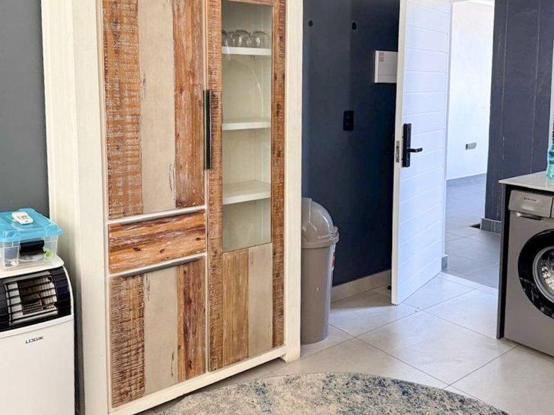 A functional laundry area featuring tiled flooring and direct access to an adjacent room through a white internal door.