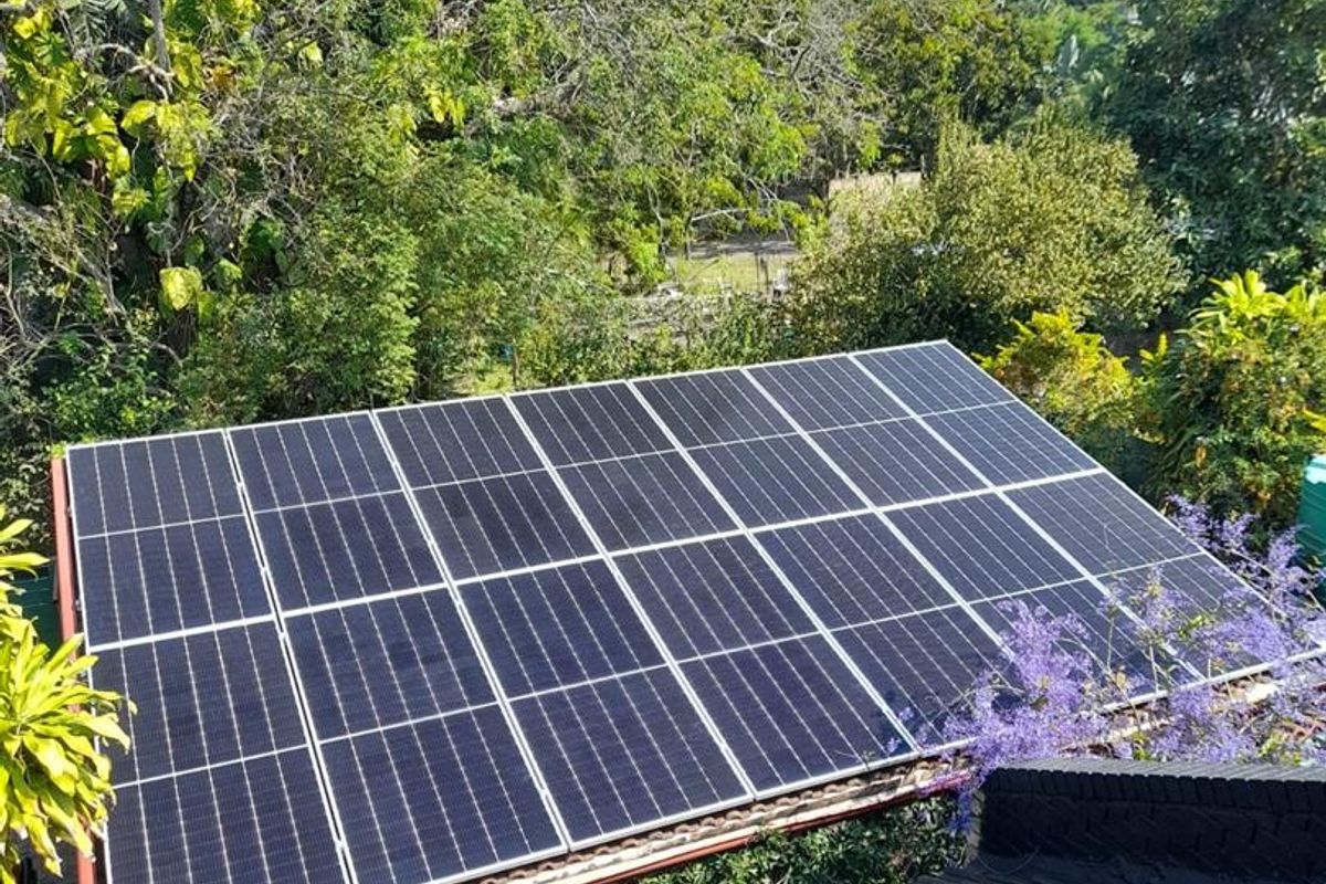 An elevated view of a residential roof featuring a large, well-maintained array of solar photovoltaic panels.